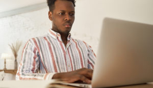 Focused young african male applying for jobs online