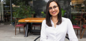 Portrait of happy female in glasses sitting in cafe.