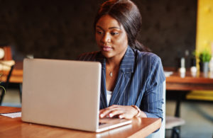 African american businesswoman sitting at table in cafe. Black girl working with laptop.